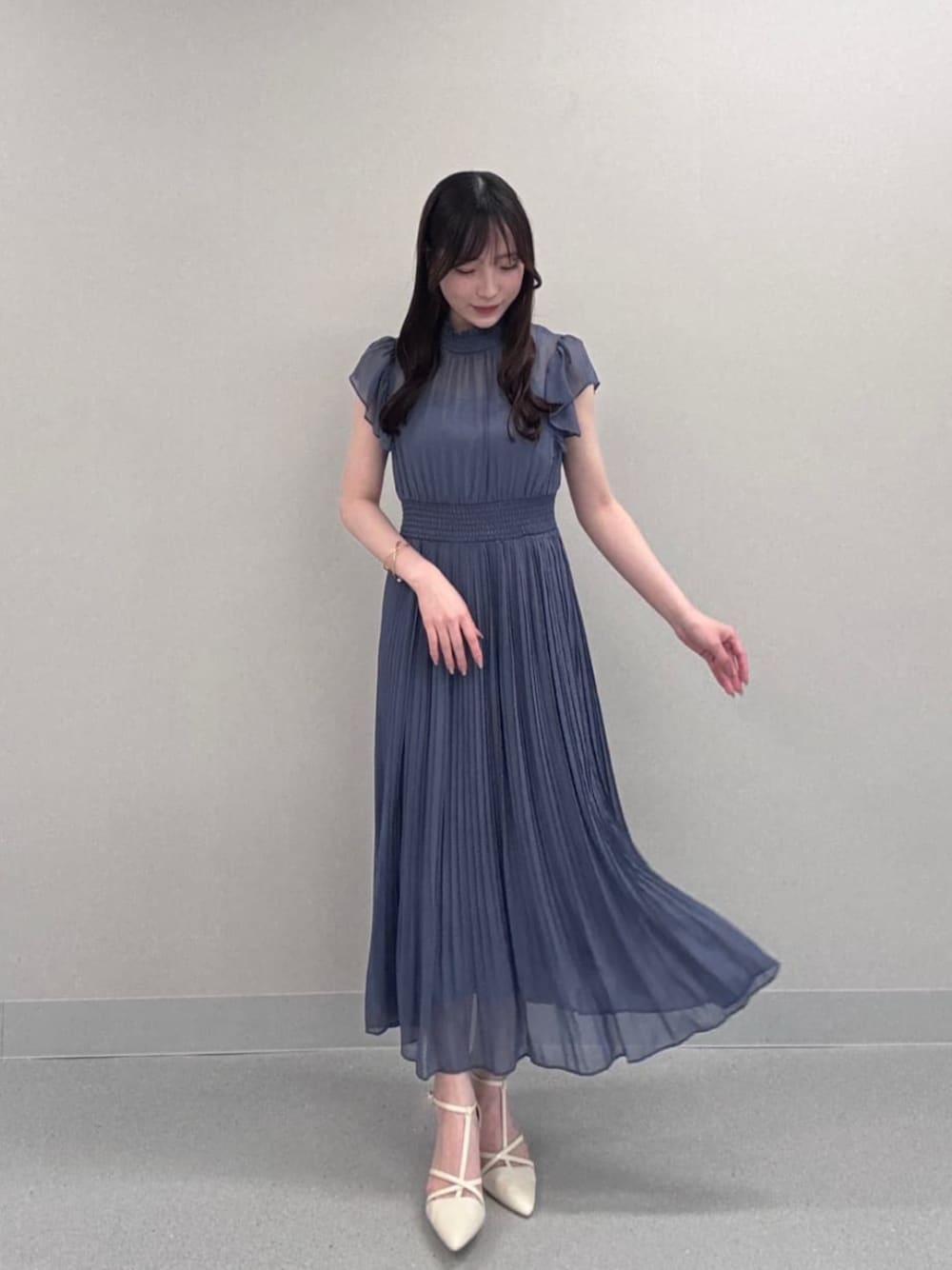 ホワイト系のパンプス、ブルー系のワンピースを着用したレディースの秋コーディネートの1枚目の写真