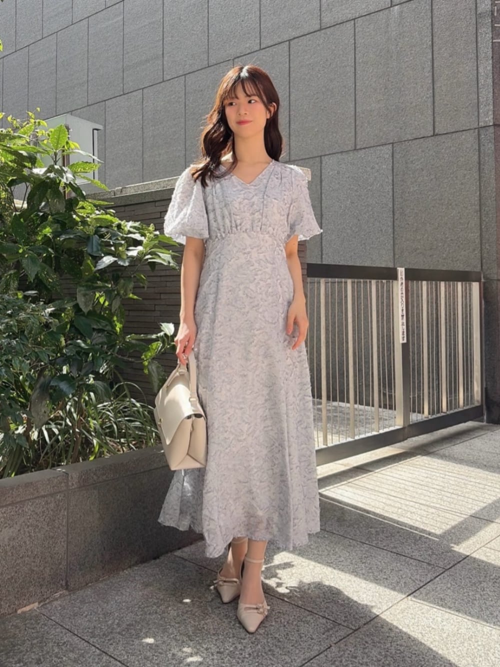 ベージュ系のパンプス、ブルー系のワンピースを着用したレディースの春コーディネートの1枚目の写真