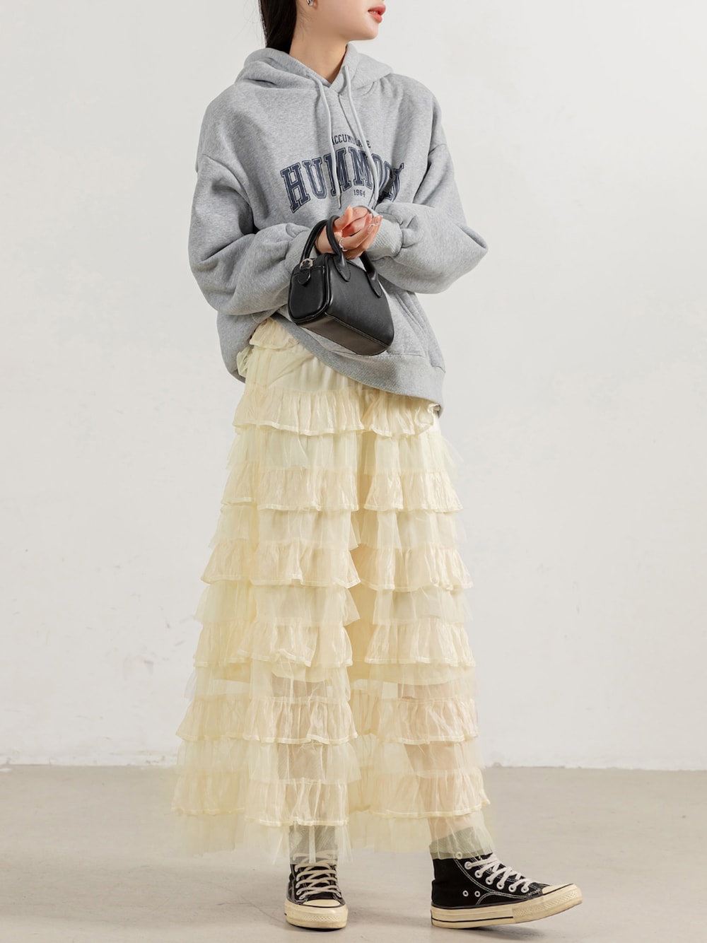 グレー系のスウェット、ホワイト系のスカートを着用したレディースの春コーディネートの1枚目の写真