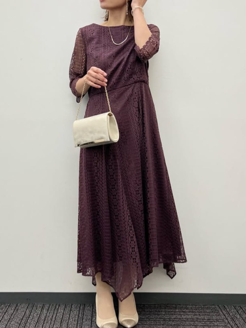 ベージュ系のクラッチバッグ、レッド系のドレス、ベージュ系のパンプスを着用したレディースの春コーディネートの1枚目の写真