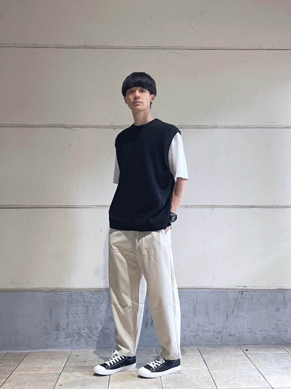 ホワイト系のTシャツ/カットソー、ブラック系のベスト、ベージュ系のパンツを着用したメンズの秋コーディネートの1枚目の写真