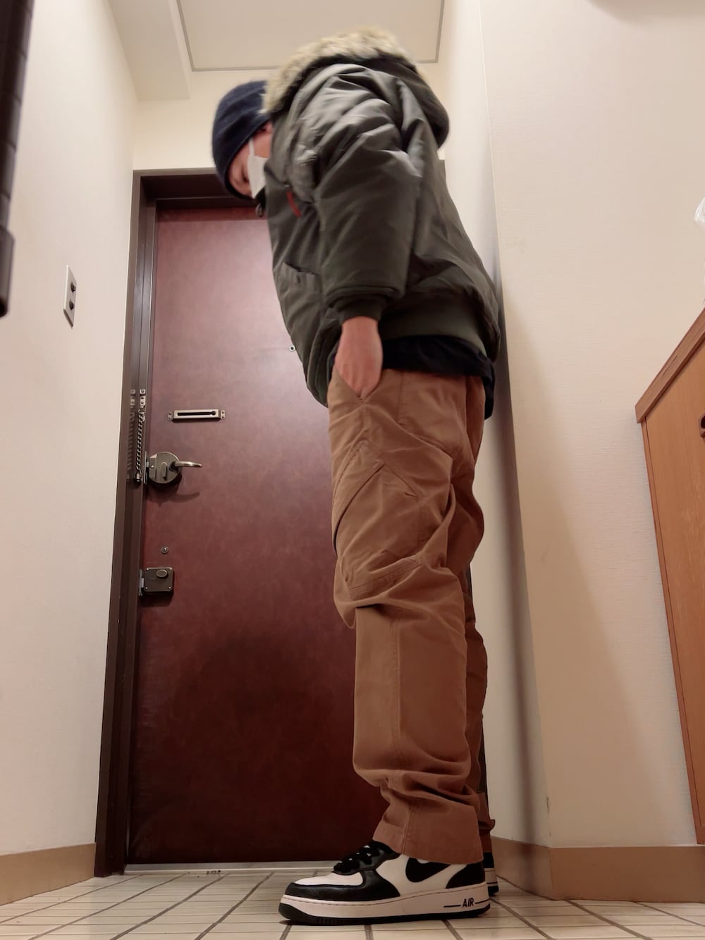 ブラック系のスニーカー、ブラウン系のカーゴパンツ、グリーン系のミリタリージャケットを着用したメンズの秋コーディネートの1枚目の写真