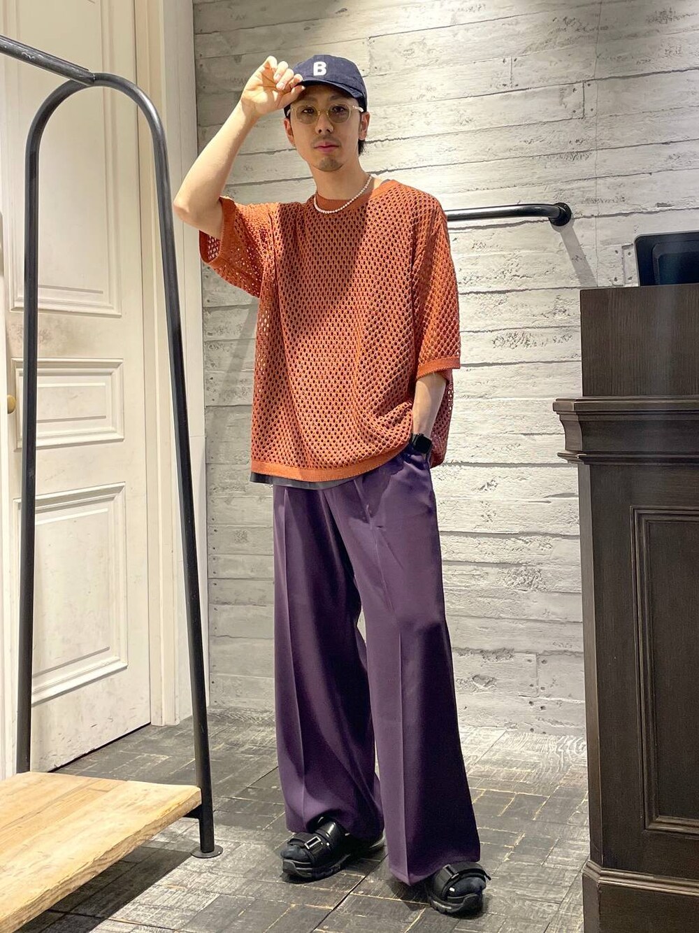 パープル系のスラックス、オレンジ系のニット/セーター、ブラック系のサンダルを着用したメンズの春コーディネートの1枚目の写真