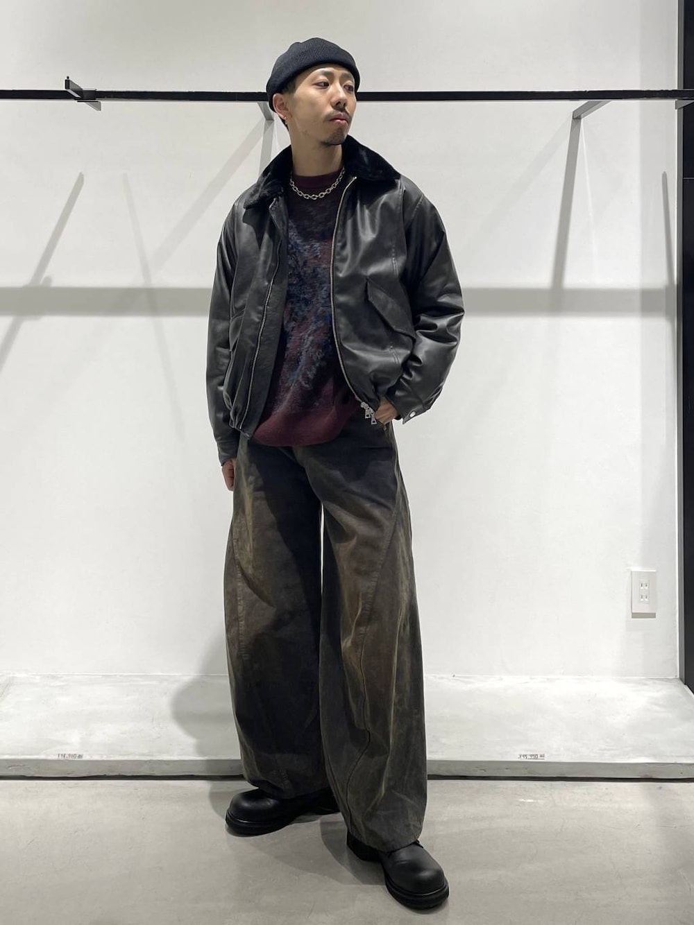 グレー系のブルゾン、レッド系のニット/セーター、ブラック系のドレスシューズを着用したメンズの秋コーディネートの1枚目の写真