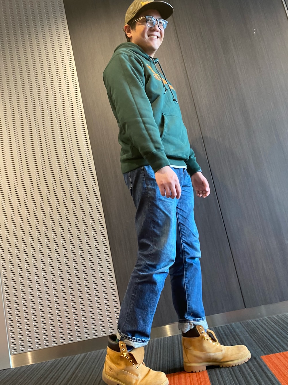 ベージュ系のブーツ、グリーン系のパーカー、ブラウン系のキャップを着用したメンズの冬コーディネートの1枚目の写真