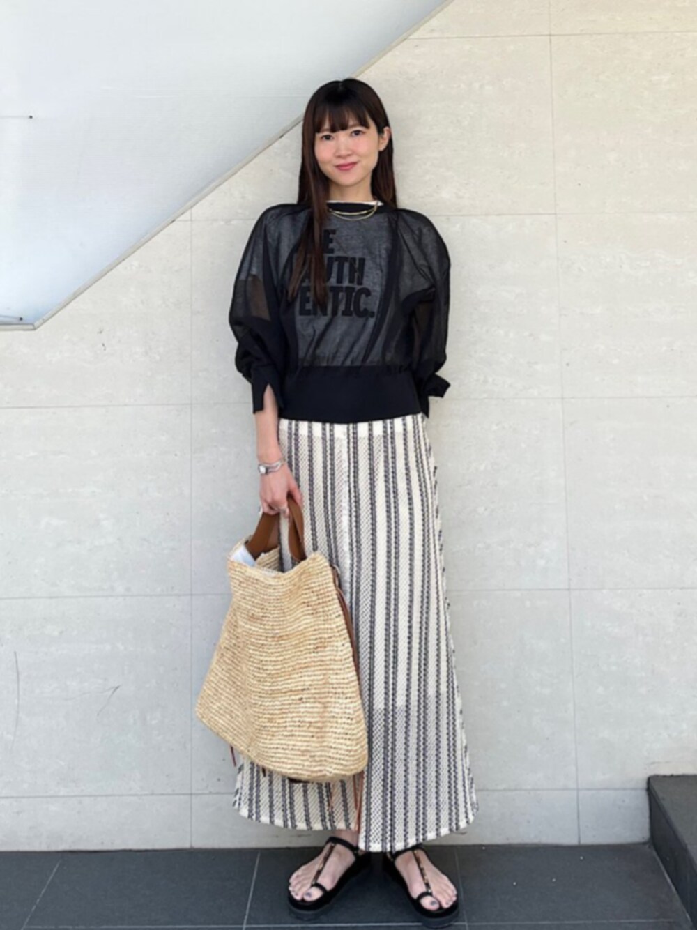 ブラウン系のトートバッグ、ホワイト系のTシャツ/カットソー、ブラック系のカーディガン/ボレロを着用したレディースの春コーディネートの1枚目の写真