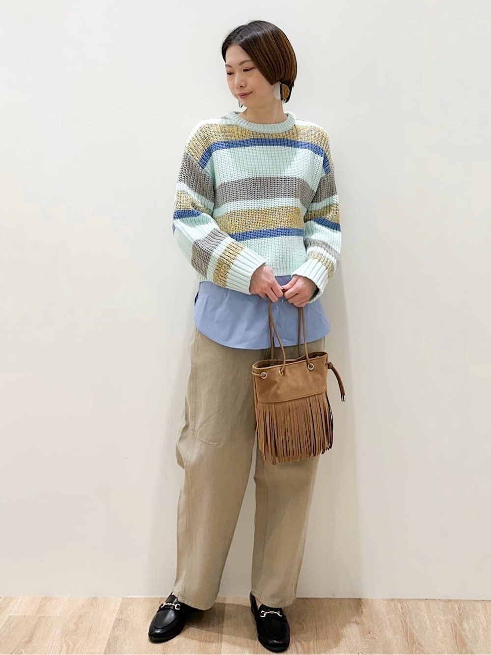 グリーン系のニット/セーター、ブルー系のTシャツ/カットソー、ベージュ系のデニムパンツを着用したレディースの冬コーディネートの1枚目の写真