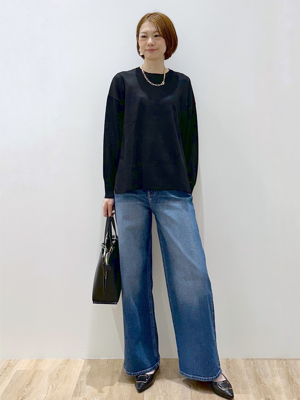 ブラック系のニット/セーター、ブルー系のデニムパンツ、ブラック系のトートバッグを着用したレディースの秋コーディネートの1枚目の写真