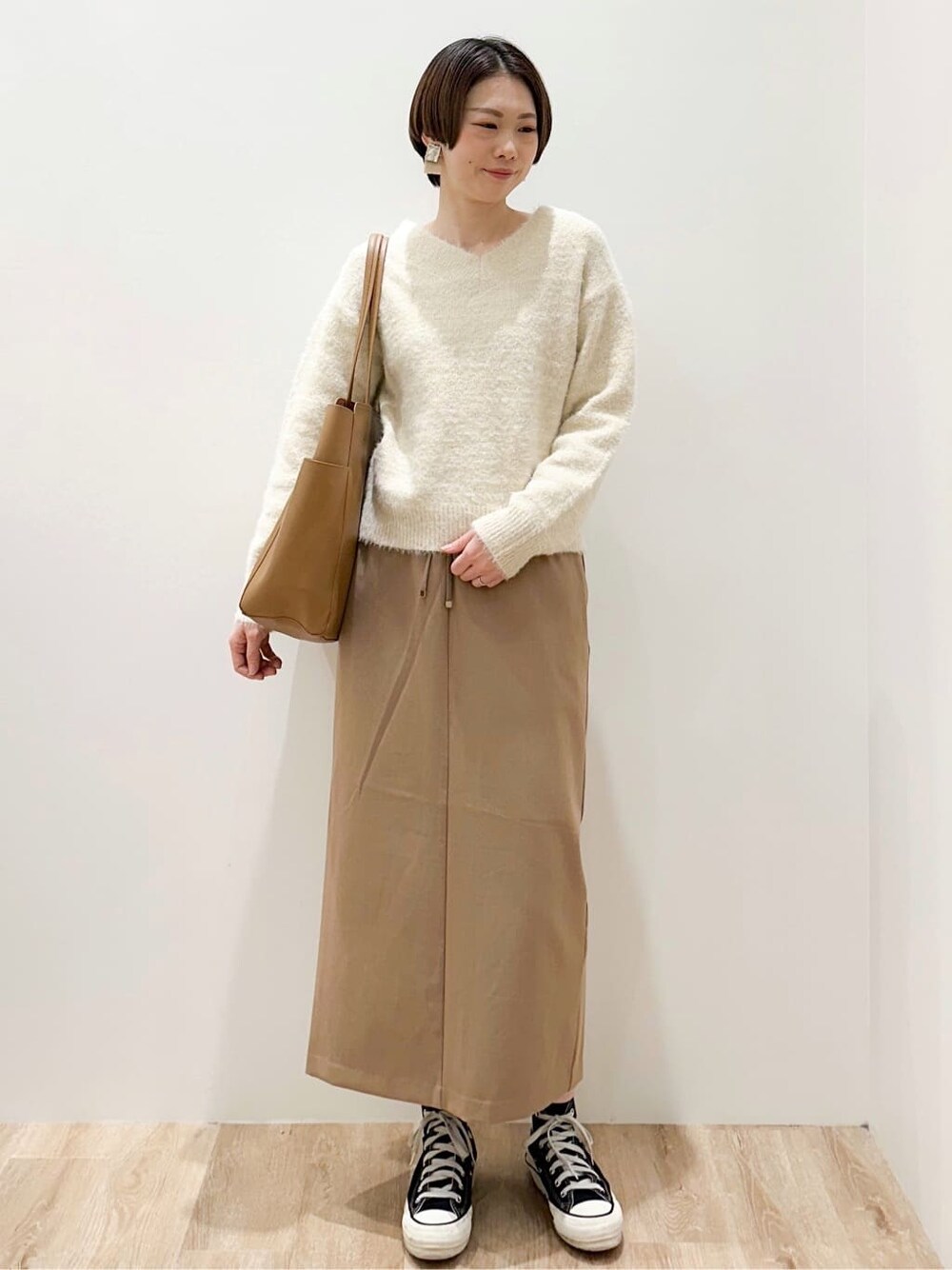 ベージュ系のニット/セーター、イエロー系のスカート、ベージュ系のトートバッグを着用したレディースの冬コーディネートの1枚目の写真