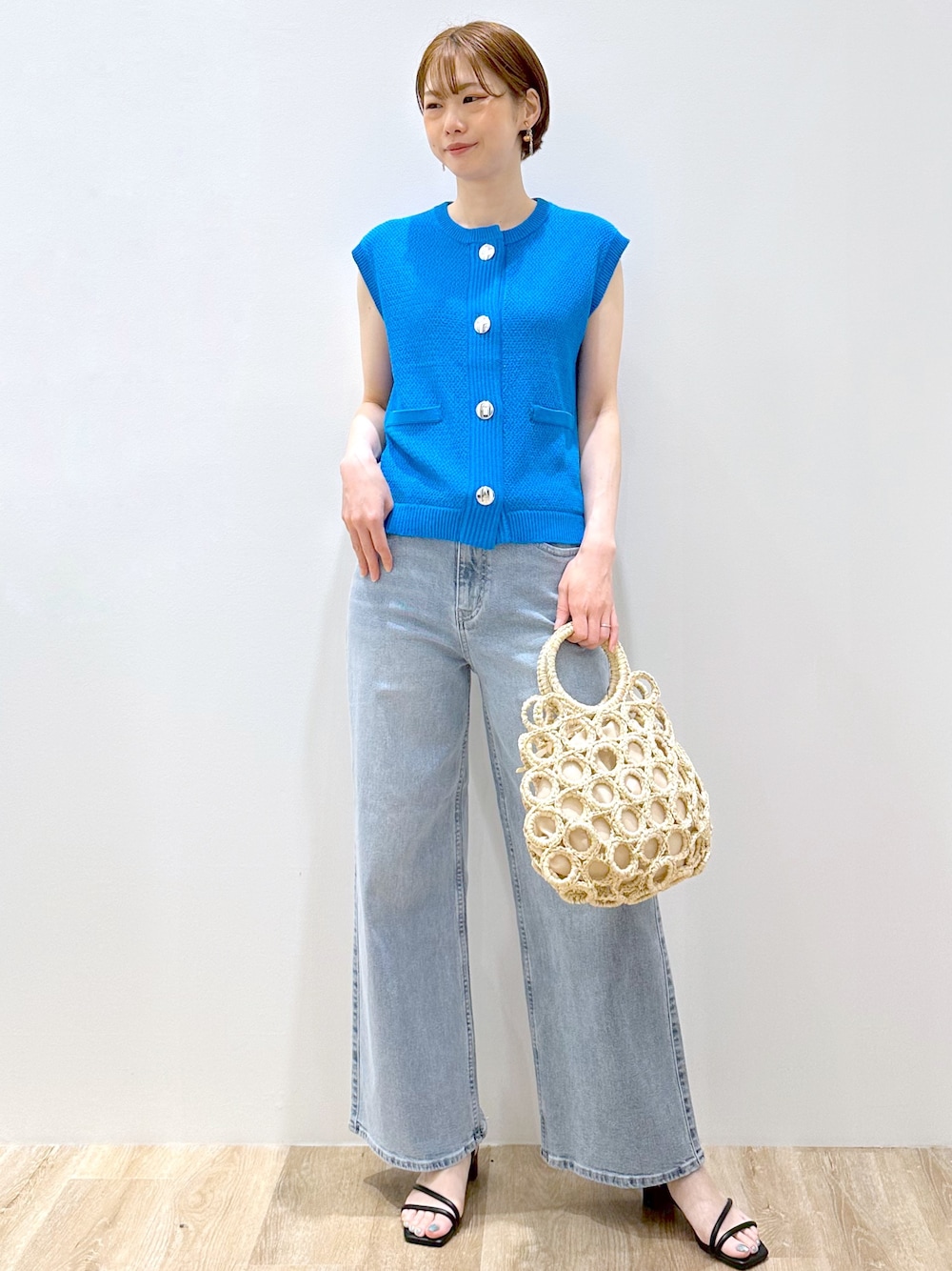 ブルー系のニット/セーター、ブルー系のデニムパンツ、ホワイト系のハンドバッグを着用したレディースの夏コーディネートの1枚目の写真