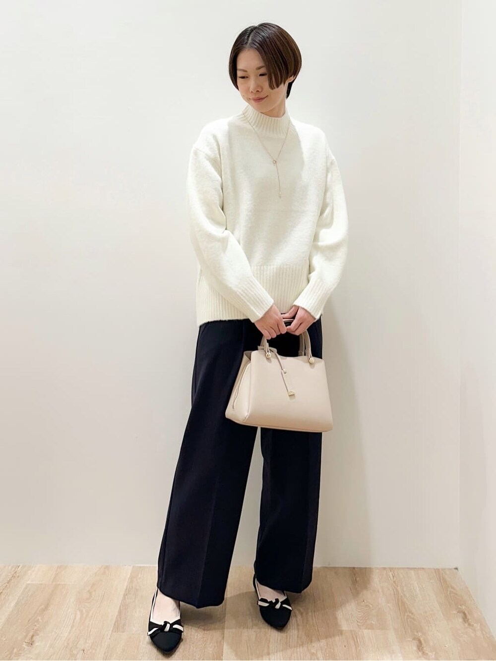 ホワイト系のニット/セーター、ブラック系のその他パンツ、ベージュ系のボストンバッグを着用したレディースの冬コーディネートの1枚目の写真
