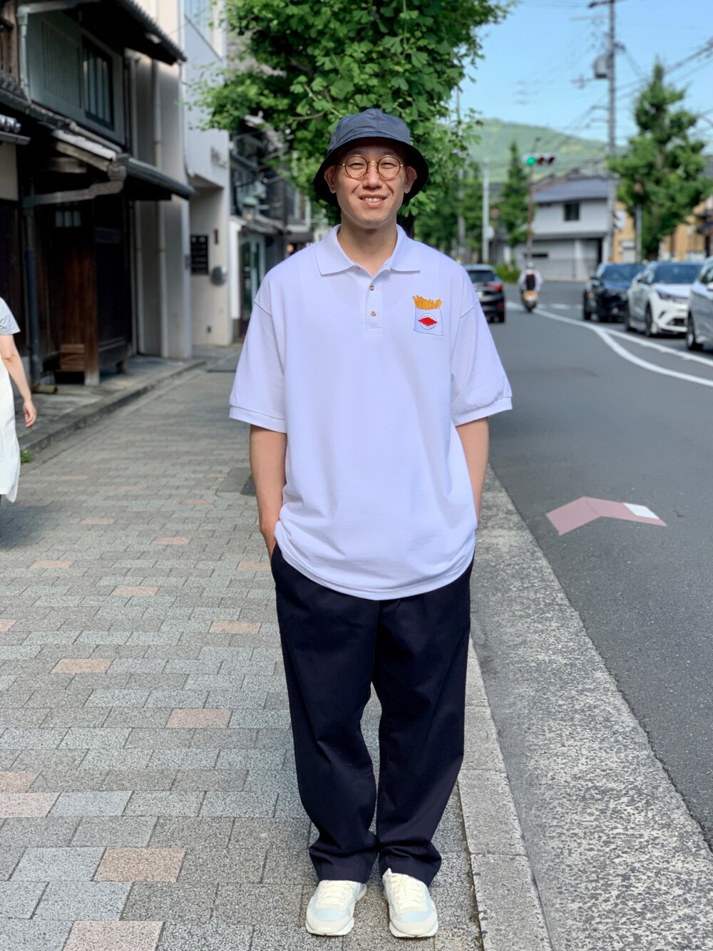 ホワイト系のポロシャツ、ブルー系のチノパンツを着用したメンズの夏コーディネートの1枚目の写真