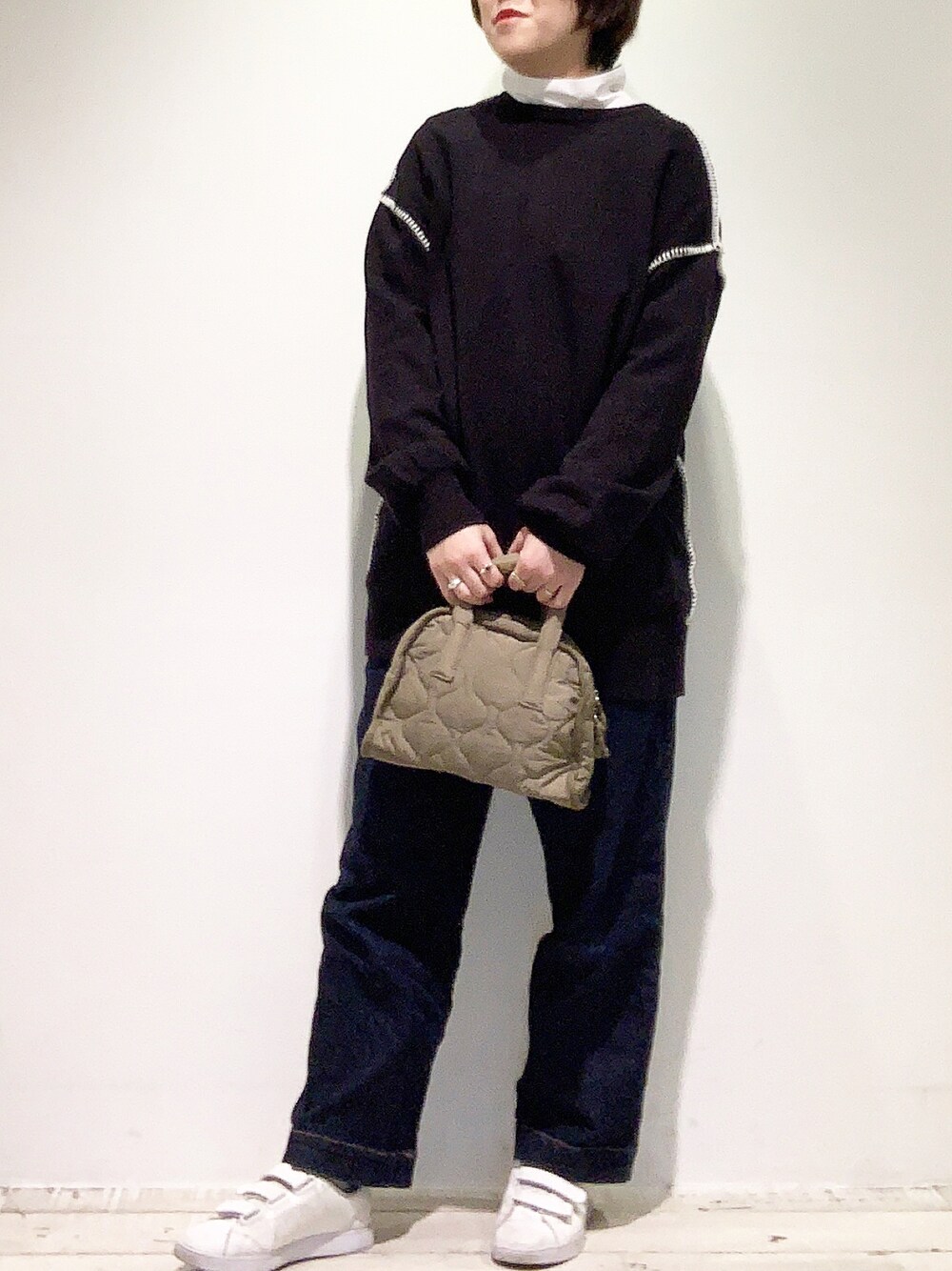 ブルー系のデニムパンツ、ホワイト系のスニーカー、グリーン系のショルダーバッグを着用したレディースの冬コーディネートの1枚目の写真