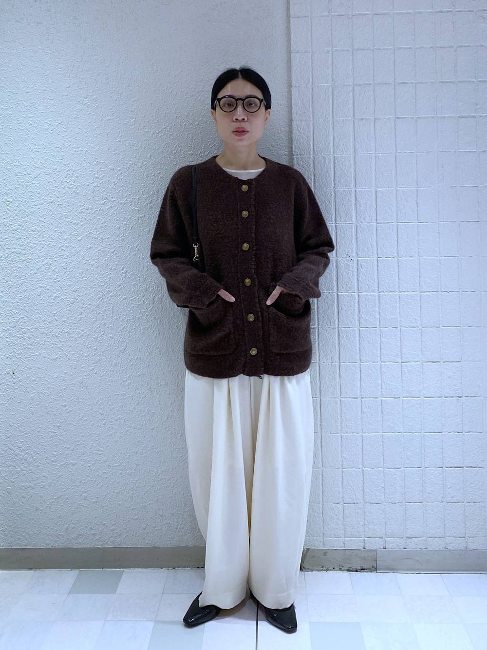 ホワイト系のスラックス、ホワイト系のTシャツ/カットソー、ブラック系のショルダーバッグを着用したレディースの秋コーディネートの1枚目の写真