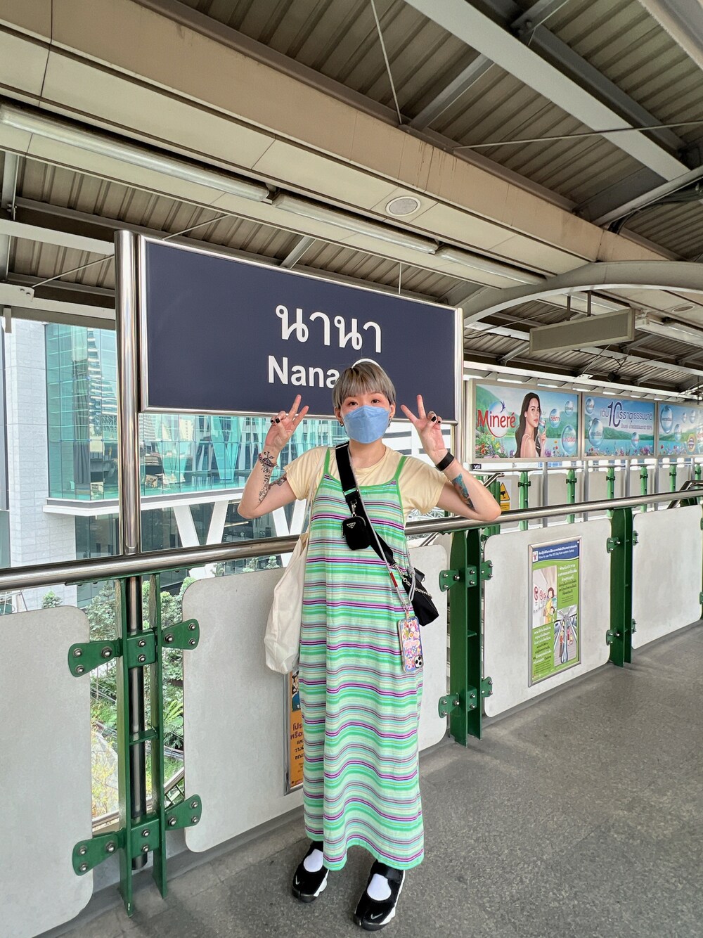 ブラック系のショルダーバッグ、グリーン系のワンピース、ブラック系のスニーカーを着用したレディースの春コーディネートの1枚目の写真