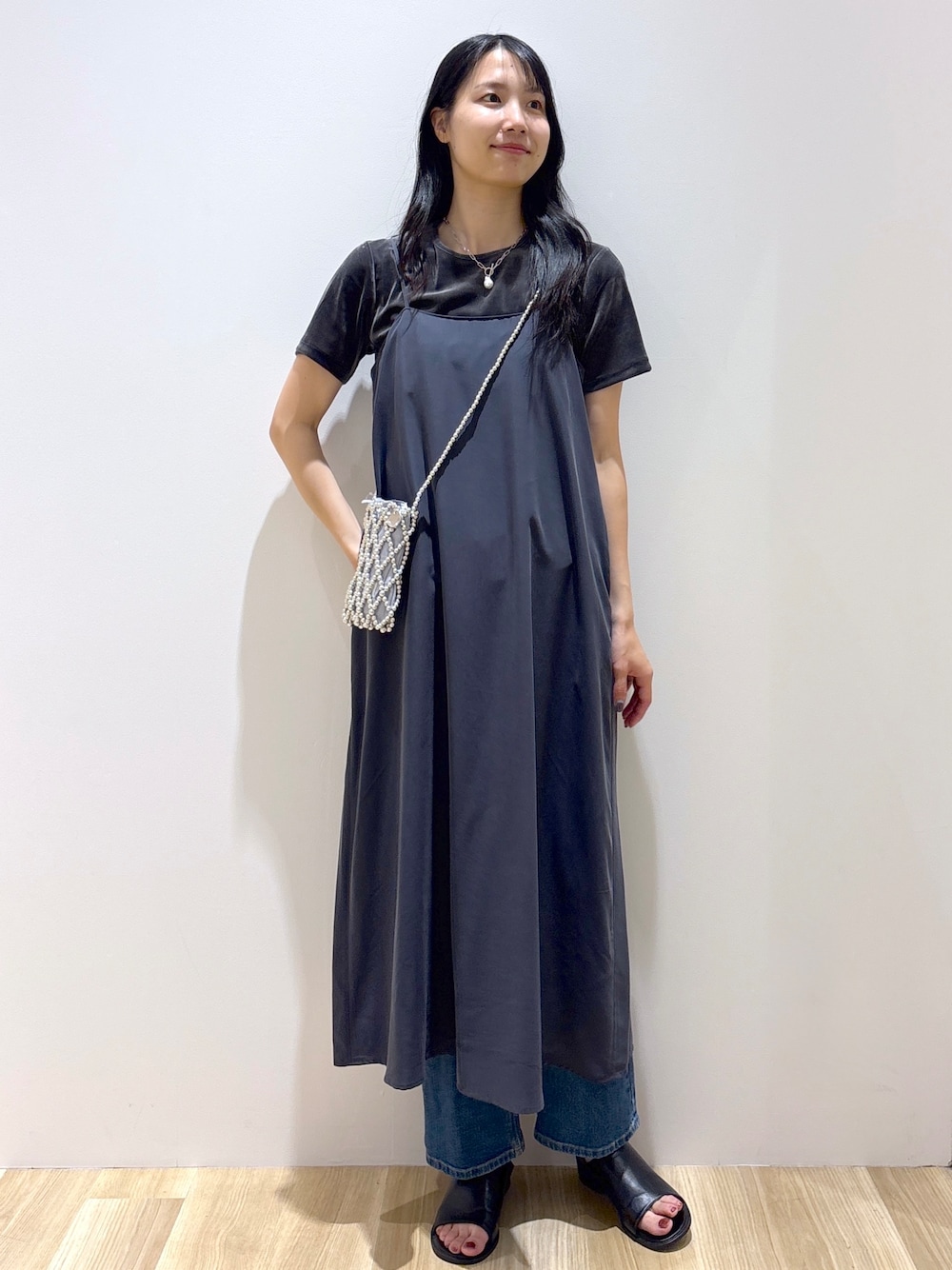 グレー系のワンピース、グレー系のTシャツ/カットソー、ブルー系のデニムパンツを着用したレディースの夏コーディネートの1枚目の写真