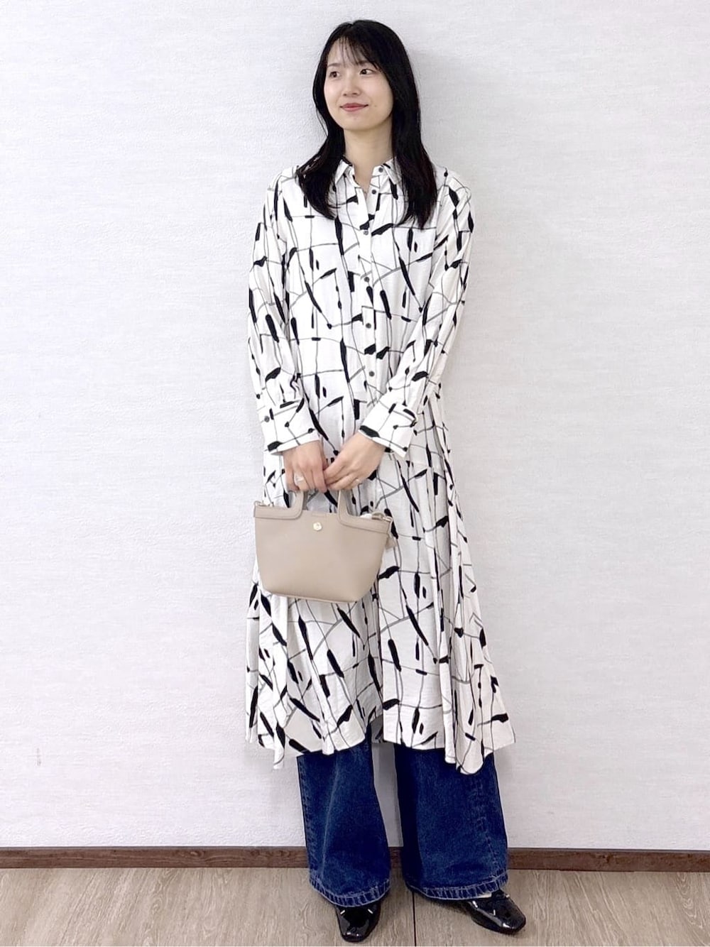 ベージュ系のワンピース、ブルー系のデニムパンツ、ベージュ系のショルダーバッグを着用したレディースの春コーディネートの1枚目の写真