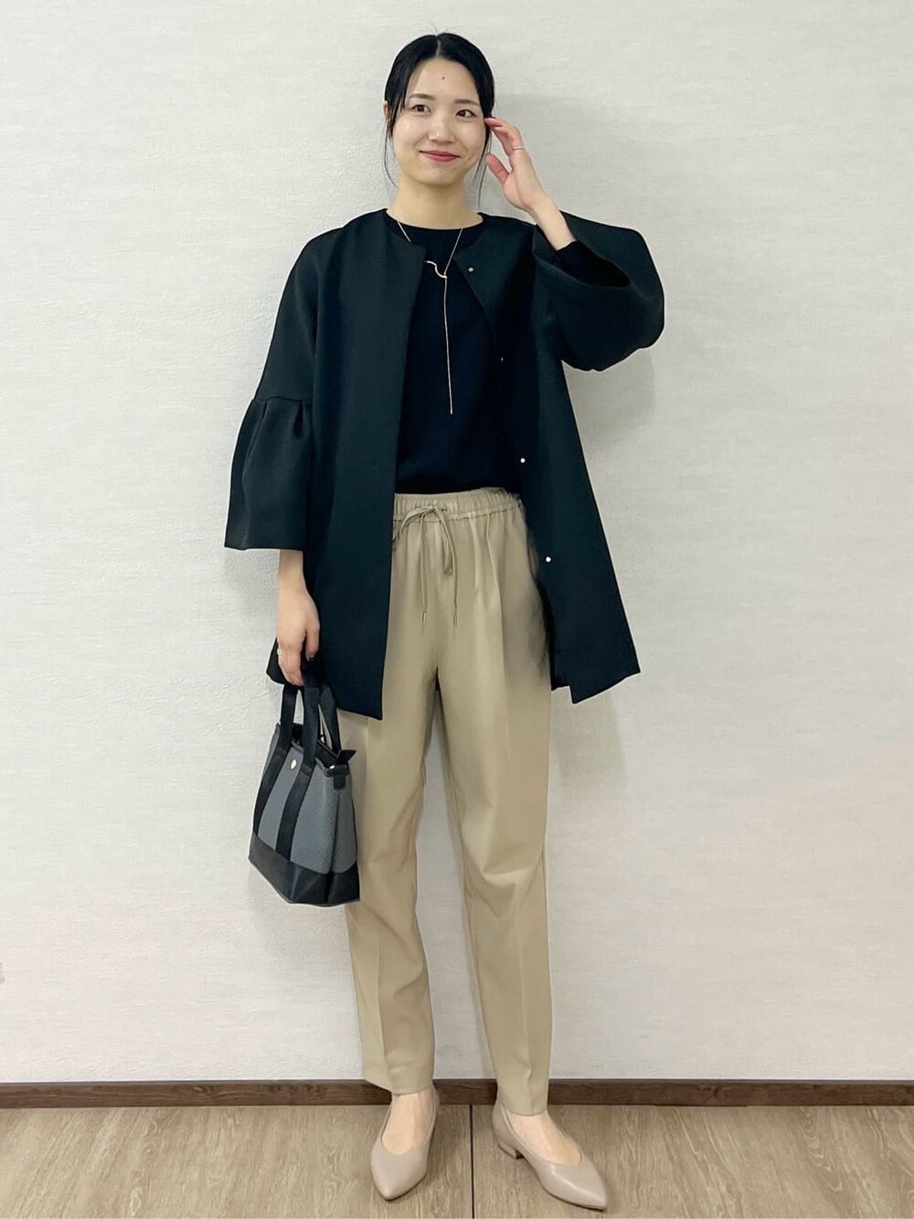 ブラック系のノーカラーコート、ブラック系のTシャツ/カットソー、ベージュ系のその他パンツを着用したレディースの冬コーディネートの1枚目の写真