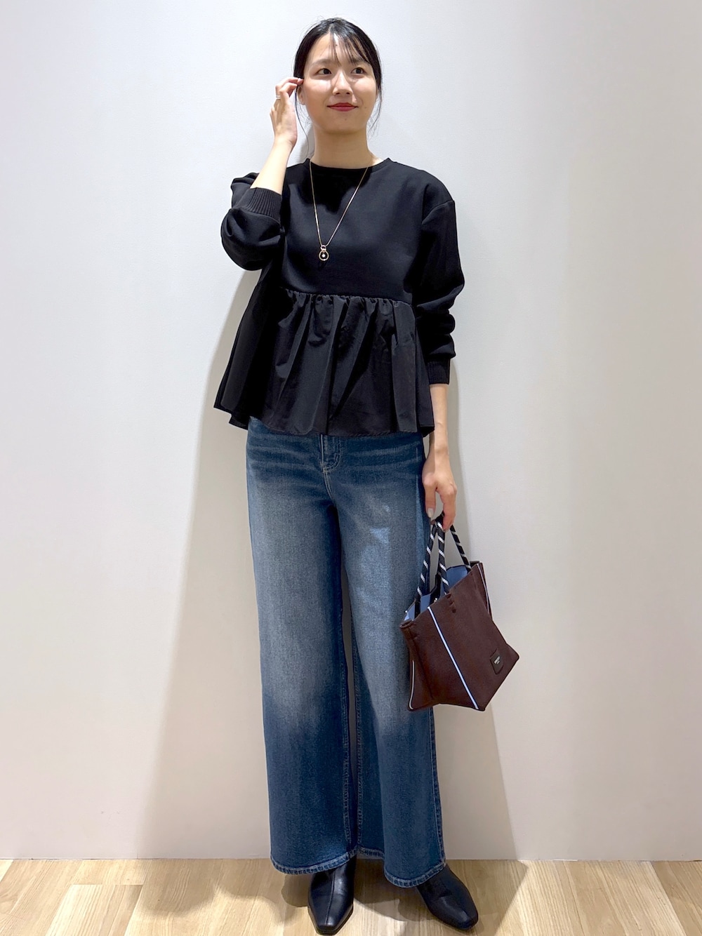 ブラック系のTシャツ/カットソー、ブルー系のデニムパンツ、ブラウン系のトートバッグを着用したレディースの秋コーディネートの1枚目の写真