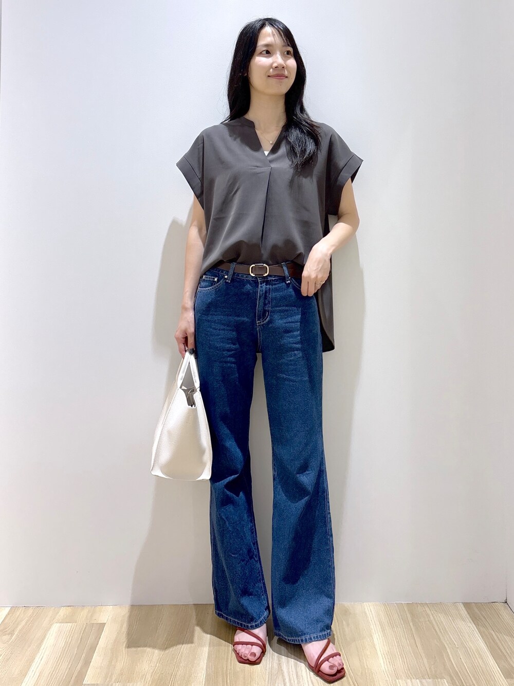 ブルー系のデニムパンツ、ホワイト系のショルダーバッグ、レッド系のサンダルを着用したレディースの夏コーディネートの1枚目の写真