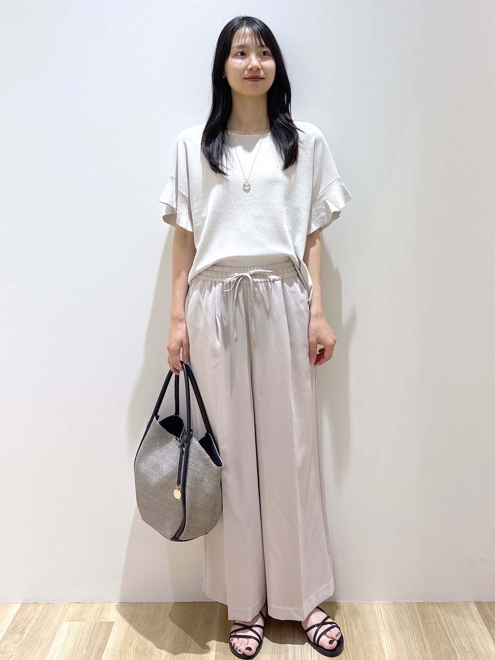 ベージュ系のその他パンツ、ブラック系のサンダル、グレー系のトートバッグを着用したレディースの春コーディネートの1枚目の写真