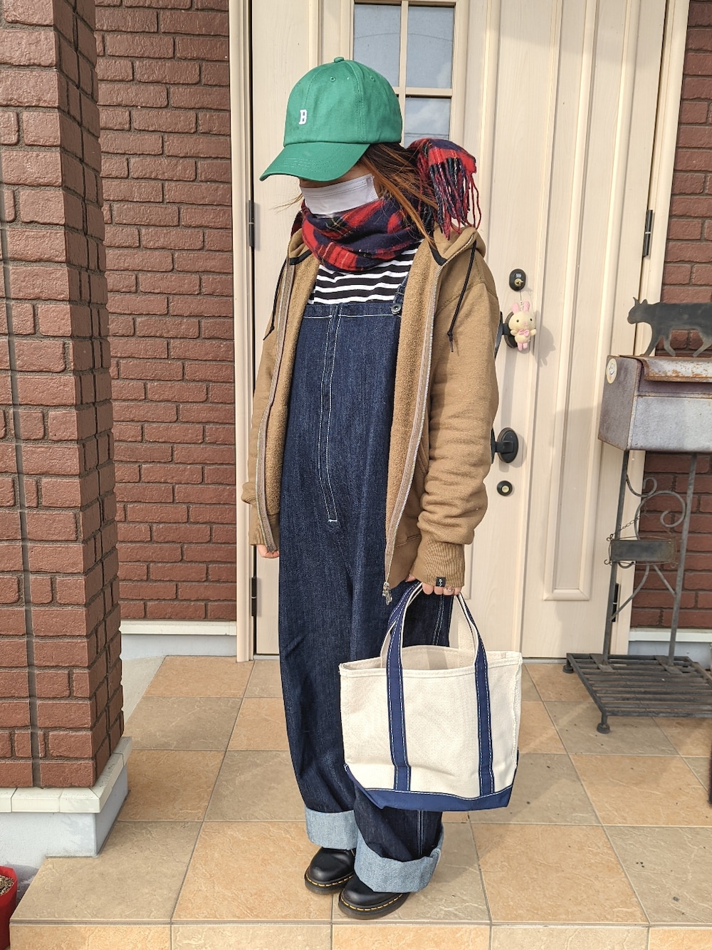 ブルー系のトートバッグ、グリーン系のパーカー、ブルー系のサロペット/オーバーオールを着用したレディースの冬コーディネートの1枚目の写真