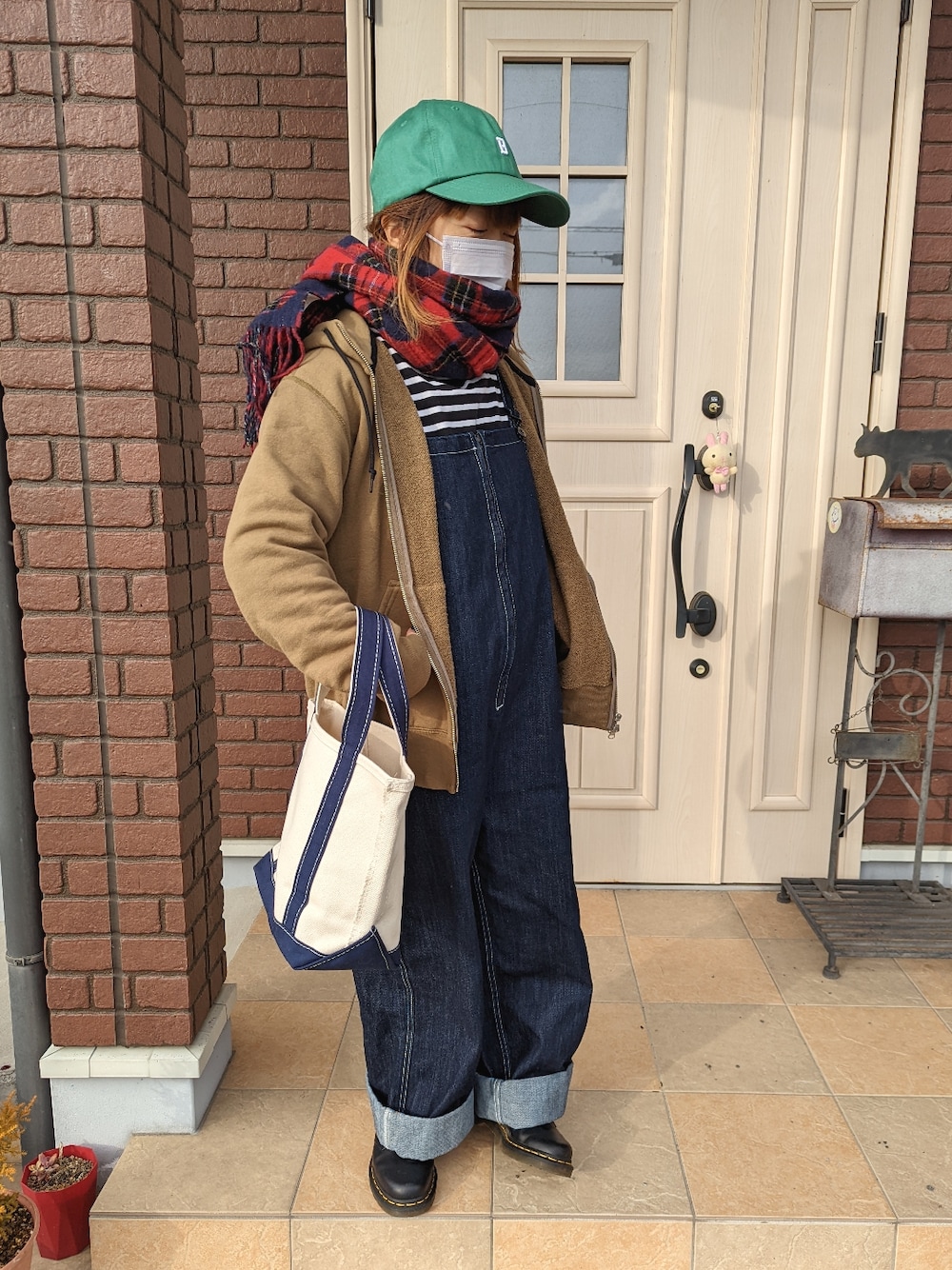 ブルー系のトートバッグ、グリーン系のパーカー、ブルー系のサロペット/オーバーオールを着用したレディースの冬コーディネートの2枚目の写真