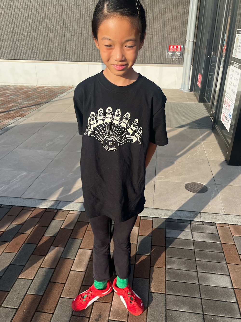 レッド系のスニーカー、ブラック系のパンツ、ブラック系のTシャツ/カットソーを着用したキッズの秋コーディネートの1枚目の写真