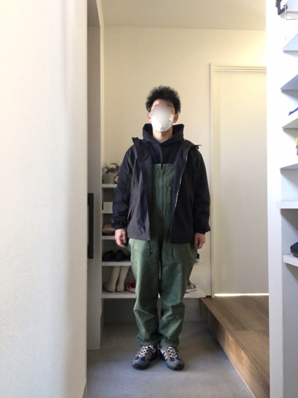 グリーン系のサロペット/オーバーオール、ブラック系のマウンテンパーカー、ブルー系のパーカーを着用したメンズの春コーディネートの1枚目の写真