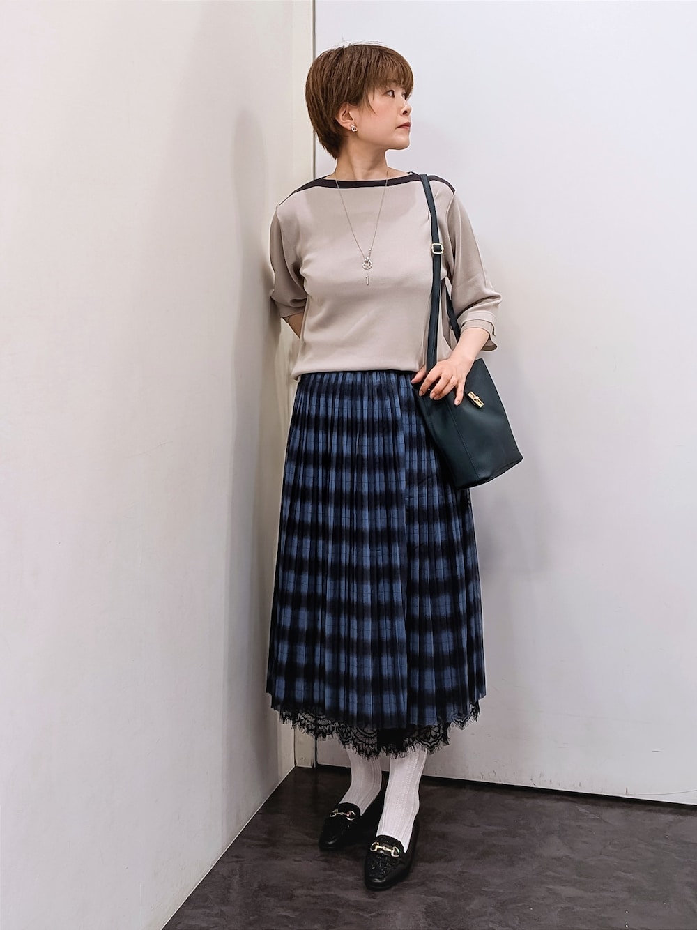 ベージュ系のニット/セーター、ホワイト系のTシャツ/カットソー、ブルー系のスカートを着用したレディースの秋コーディネートの1枚目の写真