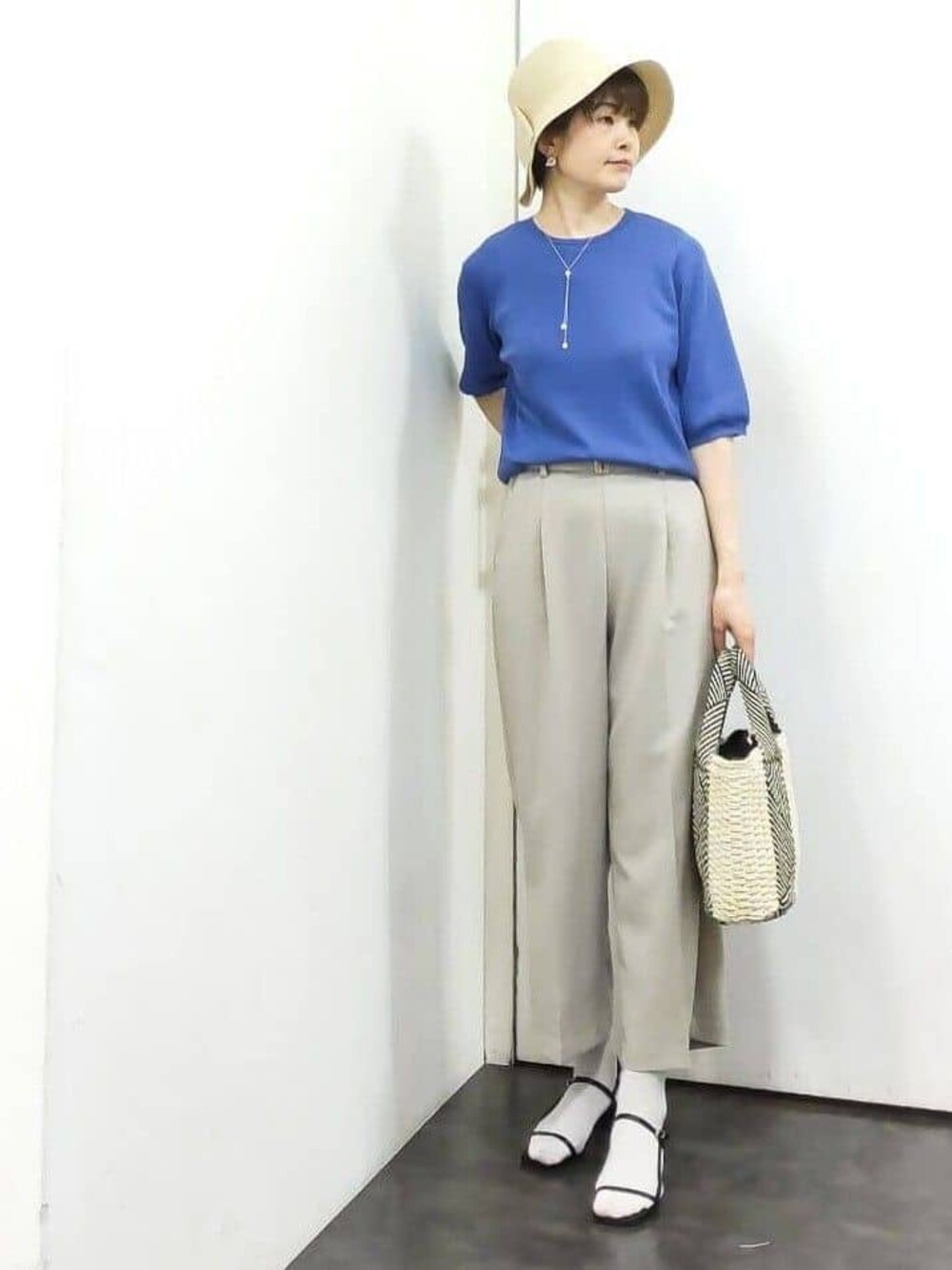 ブルー系のニット/セーター、ベージュ系のその他パンツ、ホワイト系のトートバッグを着用したレディースの春コーディネートの1枚目の写真