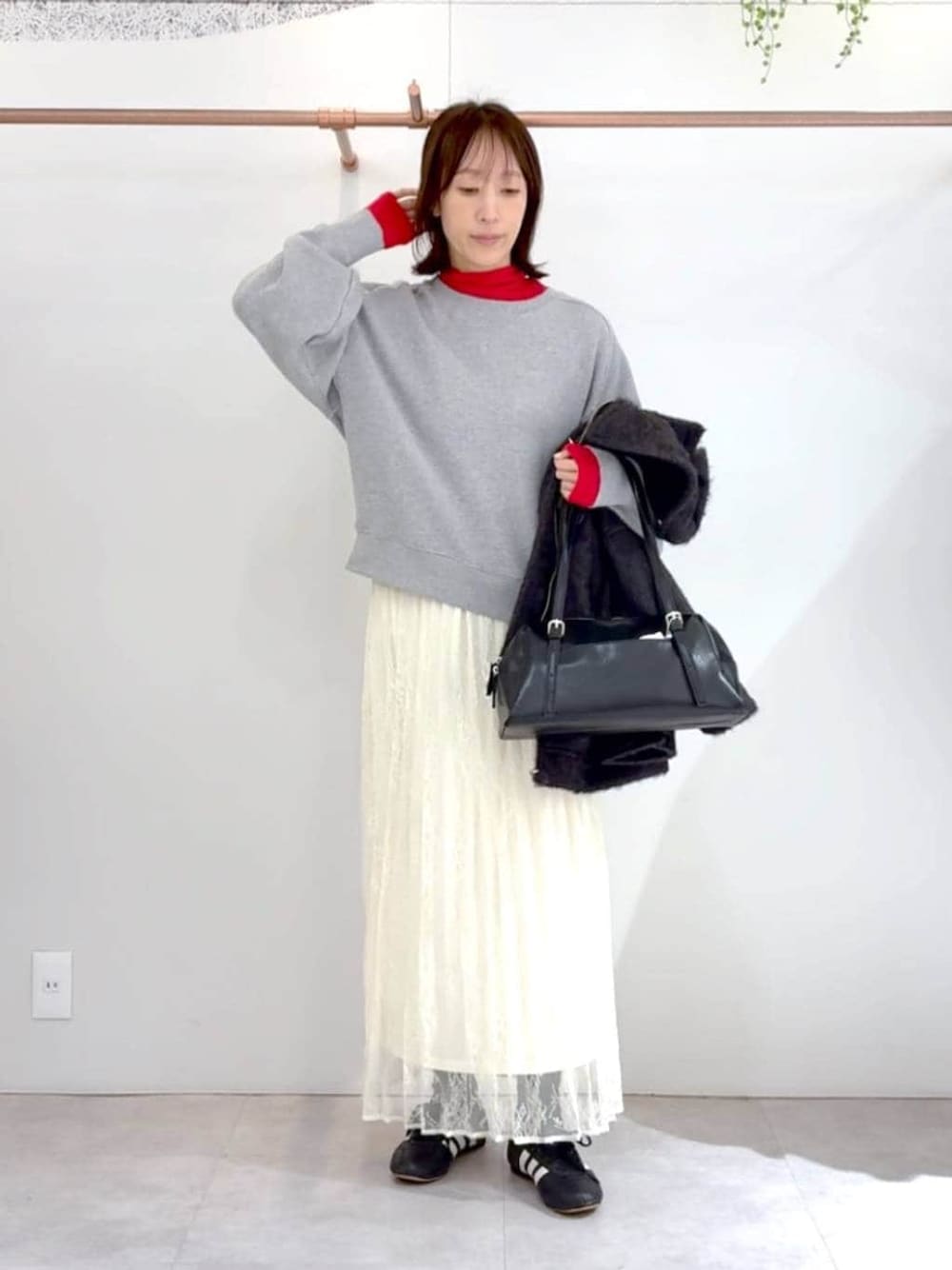 レッド系のTシャツ/カットソー、ブラック系のボストンバッグ、ホワイト系のスカートを着用したレディースの冬コーディネートの1枚目の写真