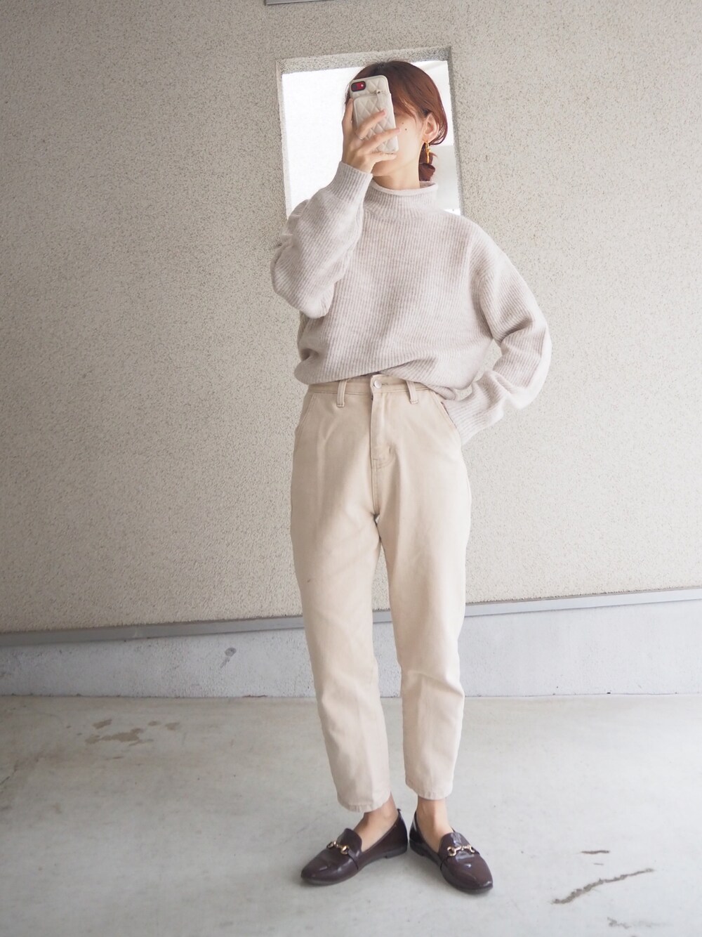 ホワイト系のニット/セーター、ブラウン系のレインシューズを着用したレディースの秋コーディネートの1枚目の写真