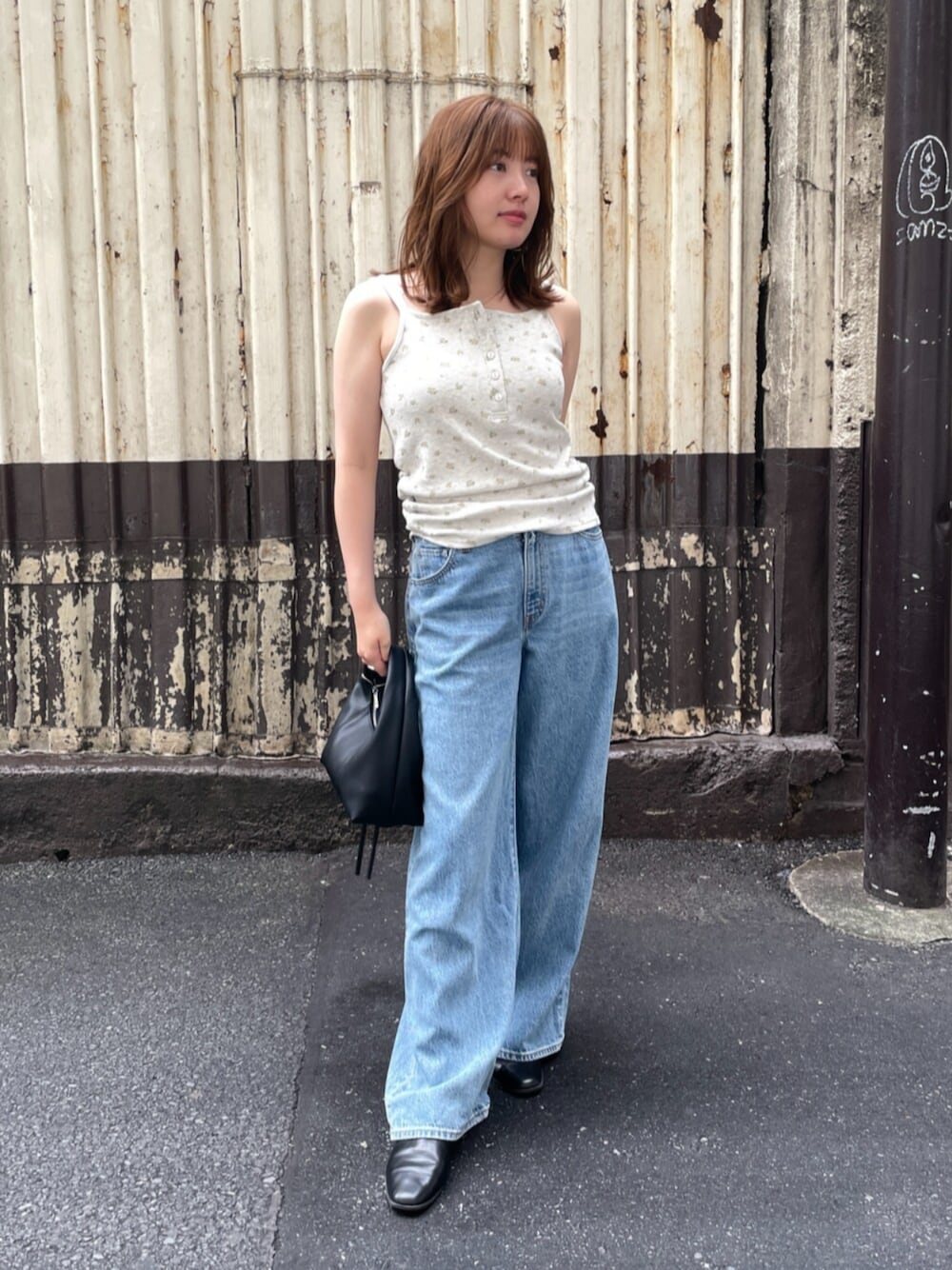 ブラック系のハンドバッグ、ブルー系のデニムパンツ、グレー系のキャミソールを着用したレディースの夏コーディネートの1枚目の写真