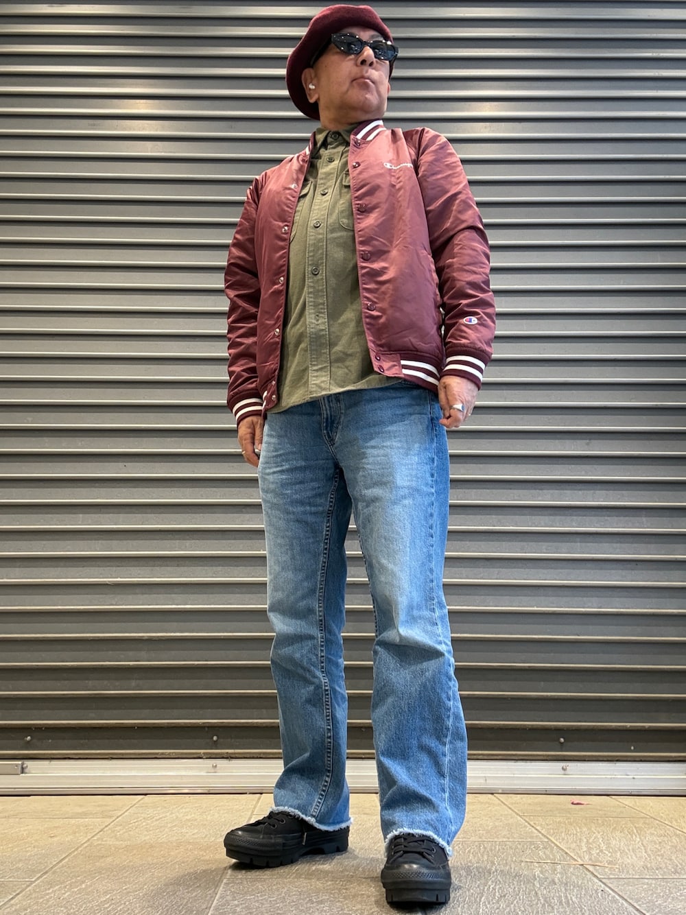 グリーン系のシャツ/ブラウス、レッド系のナイロンジャケット、ブルー系のデニムパンツを着用したメンズの春コーディネートの1枚目の写真