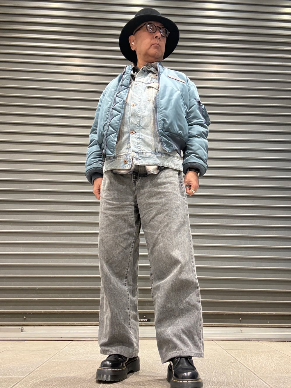 グリーン系のMA-1、ブラック系のブーツ、ブルー系のベストを着用したメンズの冬コーディネートの1枚目の写真
