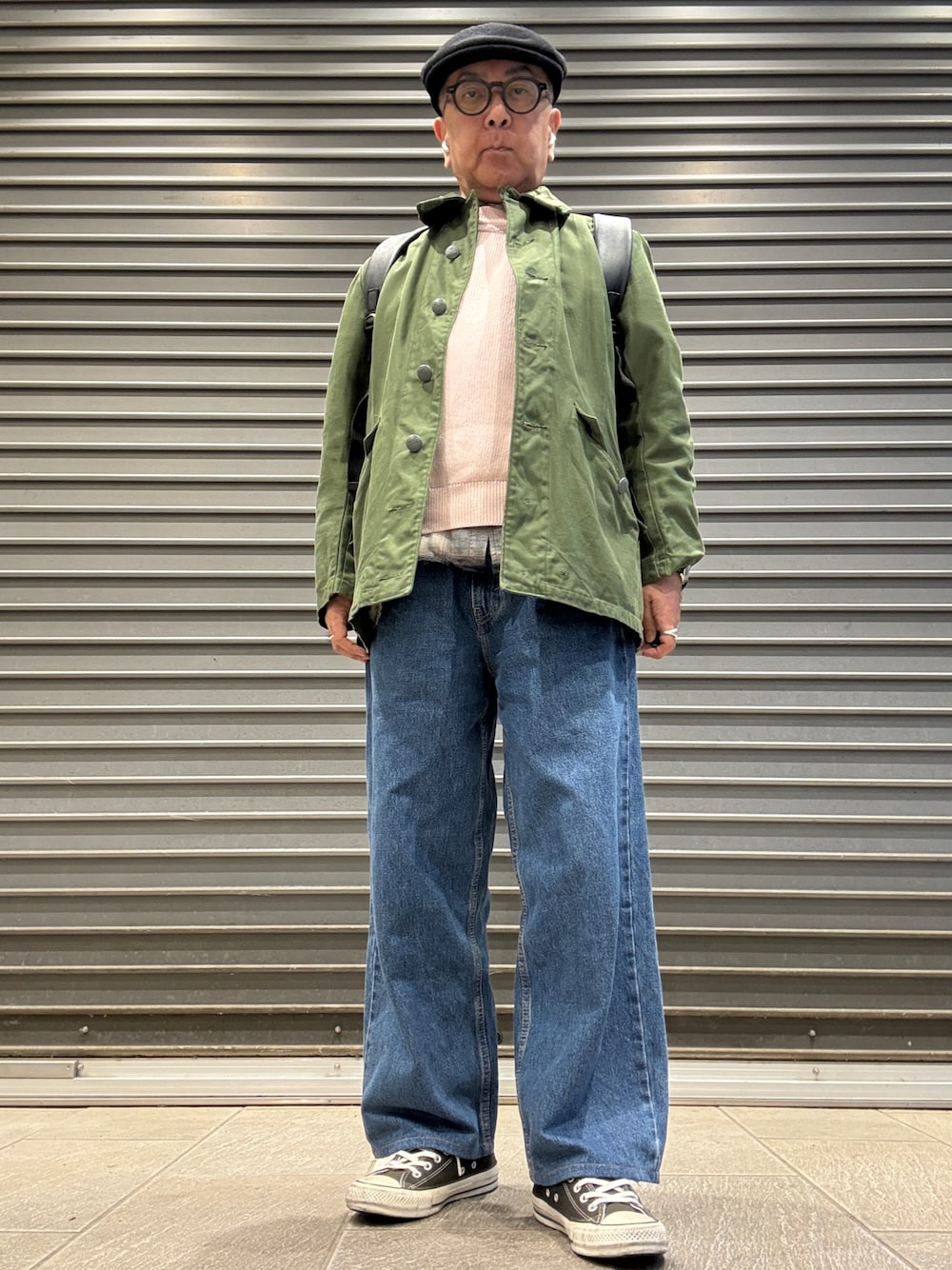 ブラック系のスニーカー、ピンク系のニット/セーター、ブラック系のシャツ/ブラウスを着用したメンズの春コーディネートの1枚目の写真