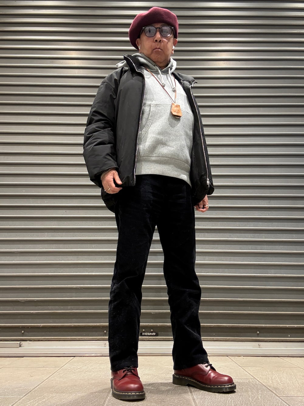 グレー系のパーカー、ブラック系のダウンジャケット/コート、レッド系のブーツを着用したメンズの冬コーディネートの1枚目の写真