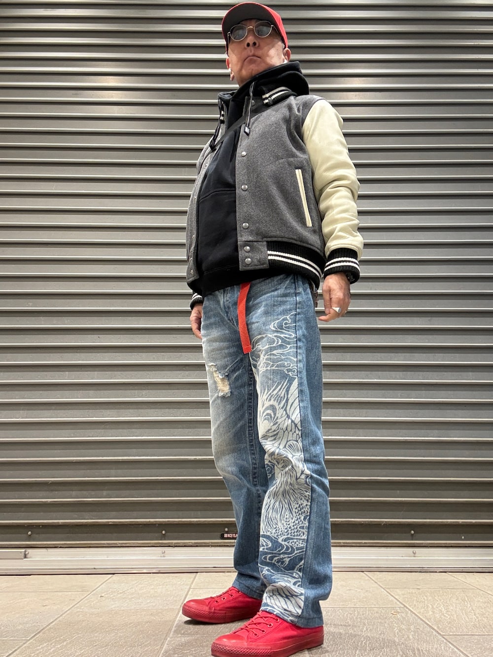 ブラック系のパーカー、グレー系のスタジャン、ブルー系のデニムパンツを着用したメンズの冬コーディネートの1枚目の写真