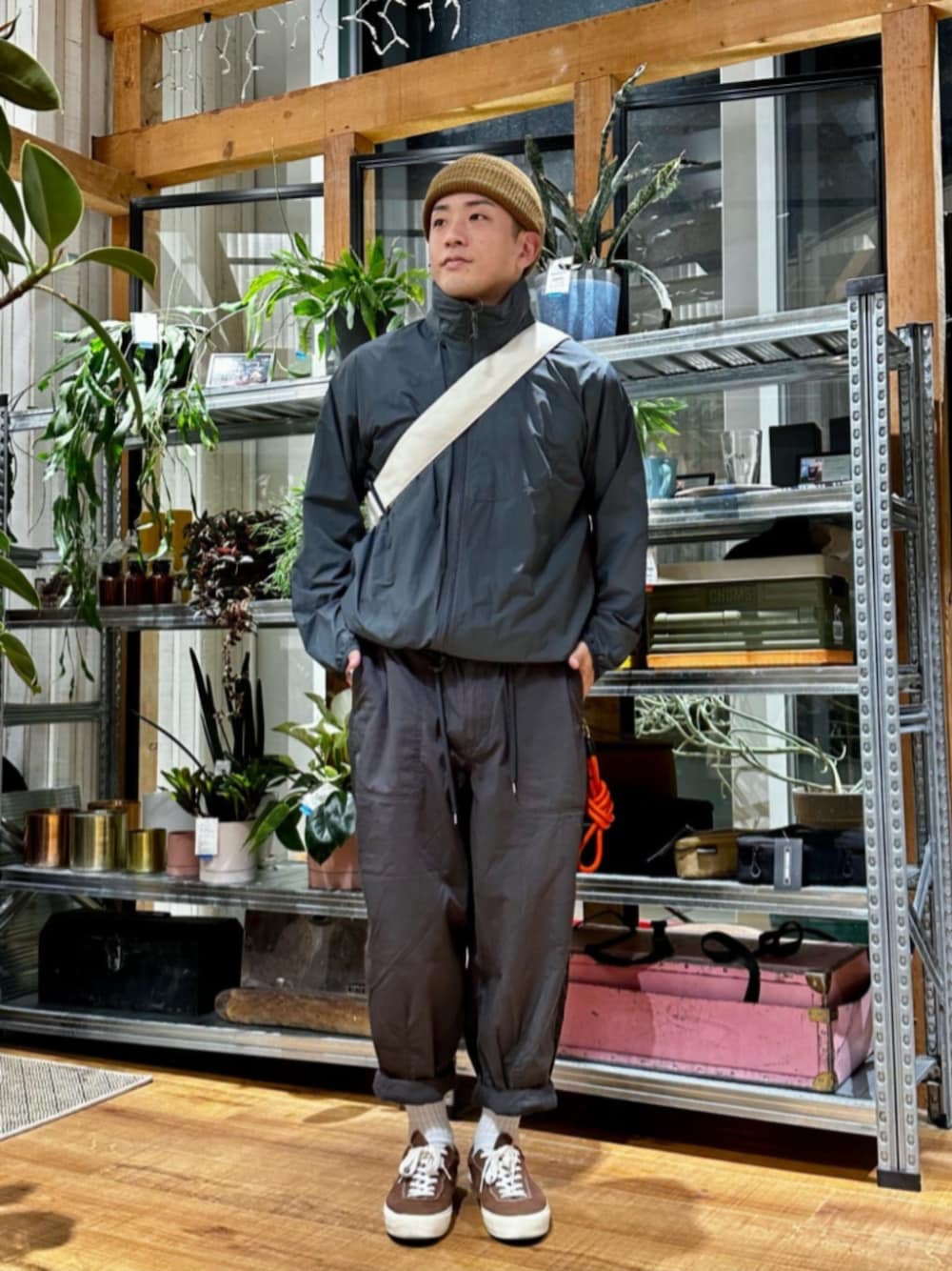 グレー系のブルゾン、ホワイト系のバッグ、オレンジ系のスマホグッズを着用したメンズの春コーディネートの1枚目の写真