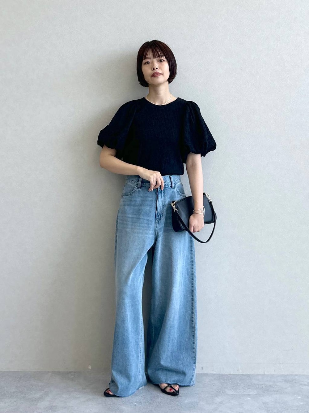 ブルー系のデニムパンツ、ブラック系のショルダーバッグ、ブラック系のサンダルを着用したレディースの春コーディネートの1枚目の写真