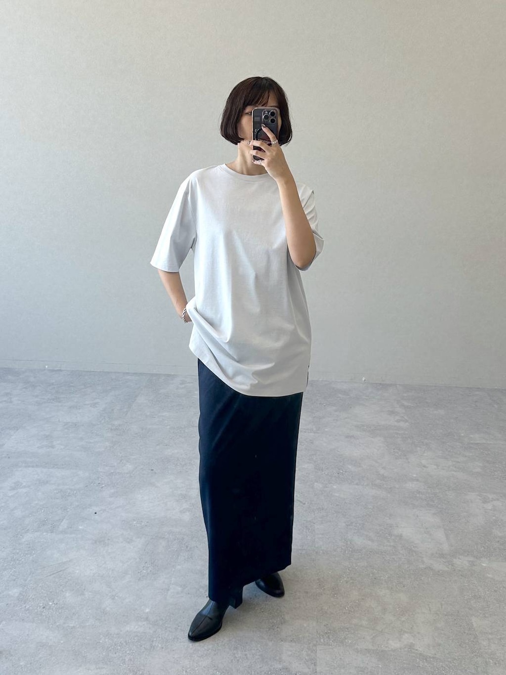 ブラック系のブーツ、ブルー系のスカート、グレー系のTシャツ/カットソーを着用したレディースの秋コーディネートの1枚目の写真