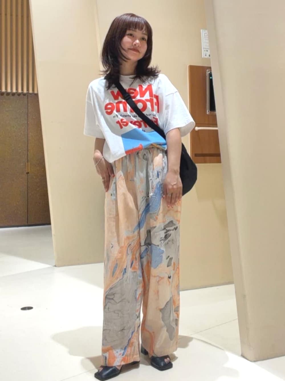 ブラック系のショルダーバッグ、オレンジ系のその他パンツ、ホワイト系のTシャツ/カットソーを着用したレディースの春コーディネートの1枚目の写真