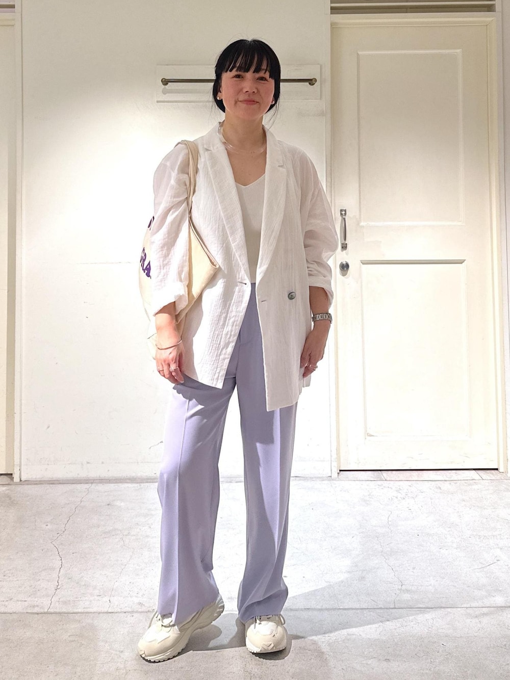 パープル系のスラックス、ホワイト系のテーラードジャケット、ホワイト系のスニーカーを着用したレディースの冬コーディネートの1枚目の写真