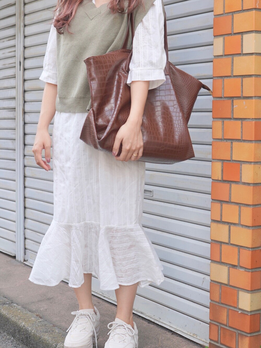 ホワイト系のワンピース、グリーン系のベスト、ブラウン系のトートバッグを着用したレディースの冬コーディネートの1枚目の写真