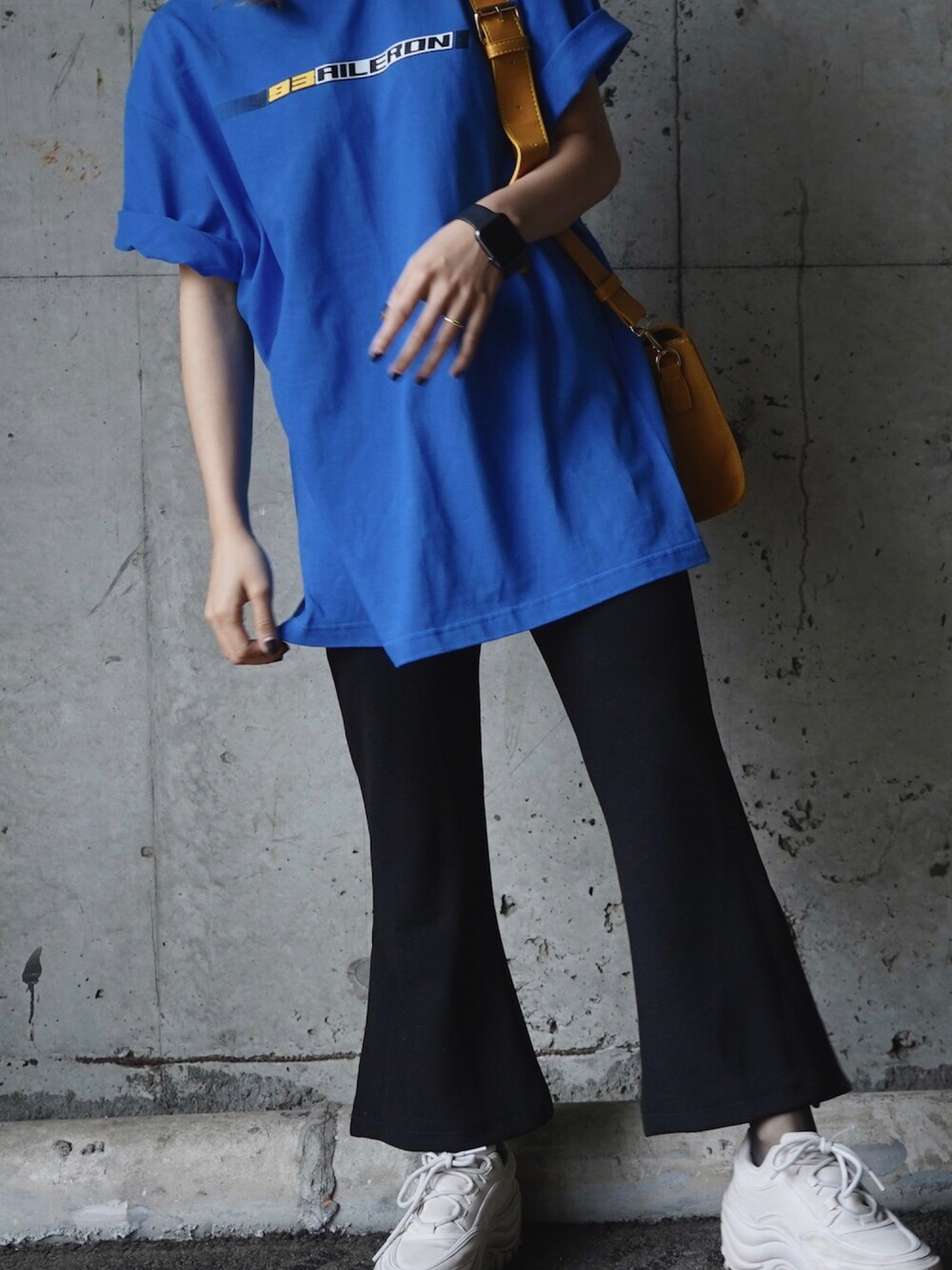 ブルー系のTシャツ/カットソー、ブラック系のスラックス、イエロー系のショルダーバッグを着用したレディースの春コーディネートの1枚目の写真