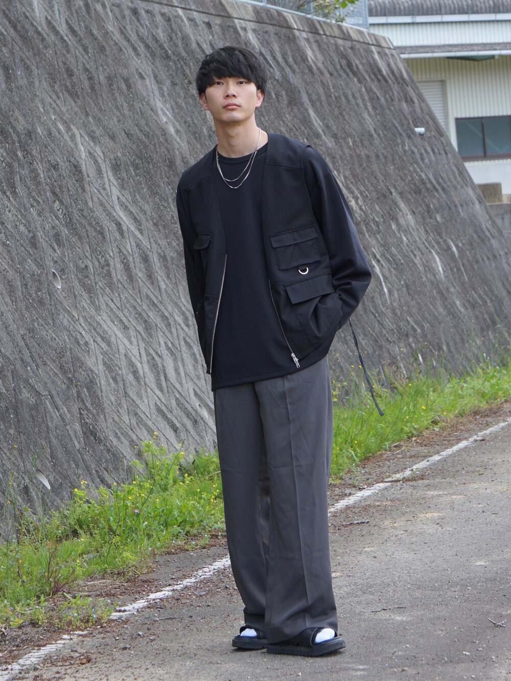 グレー系のスラックス、ブラック系のベスト、ブルー系のデニムパンツを着用したメンズの春コーディネートの1枚目の写真