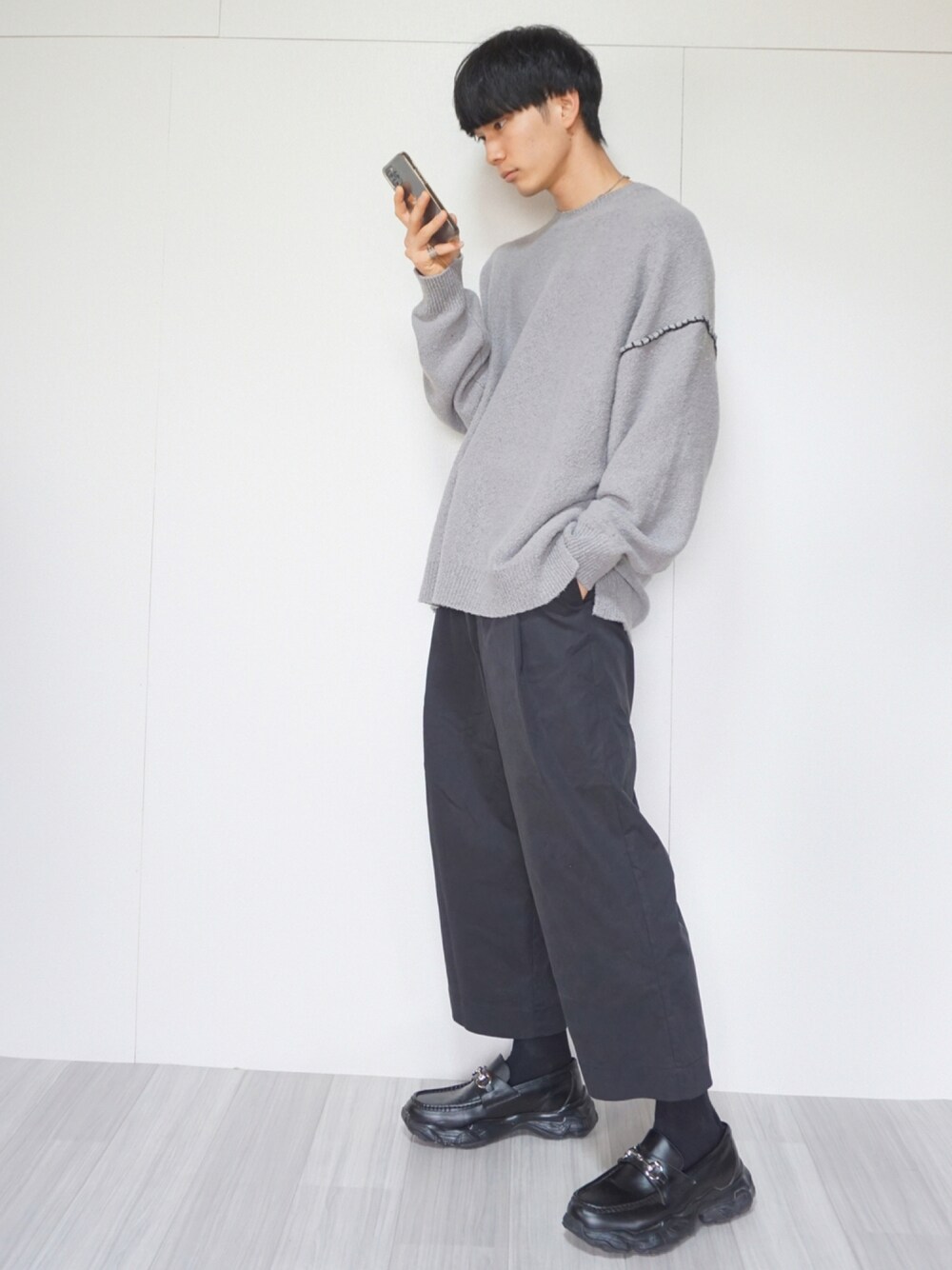 グレー系のニット/セーター、ブラック系のその他パンツ、ブラック系のスニーカーを着用したメンズの秋コーディネートの1枚目の写真