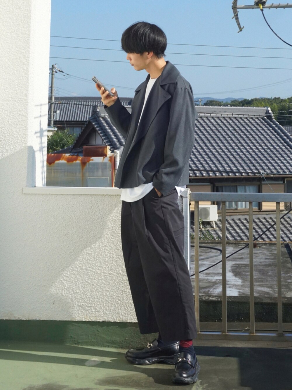 グレー系のトレンチコート、ホワイト系のTシャツ/カットソー、ブラック系のその他パンツを着用したメンズの秋コーディネートの1枚目の写真