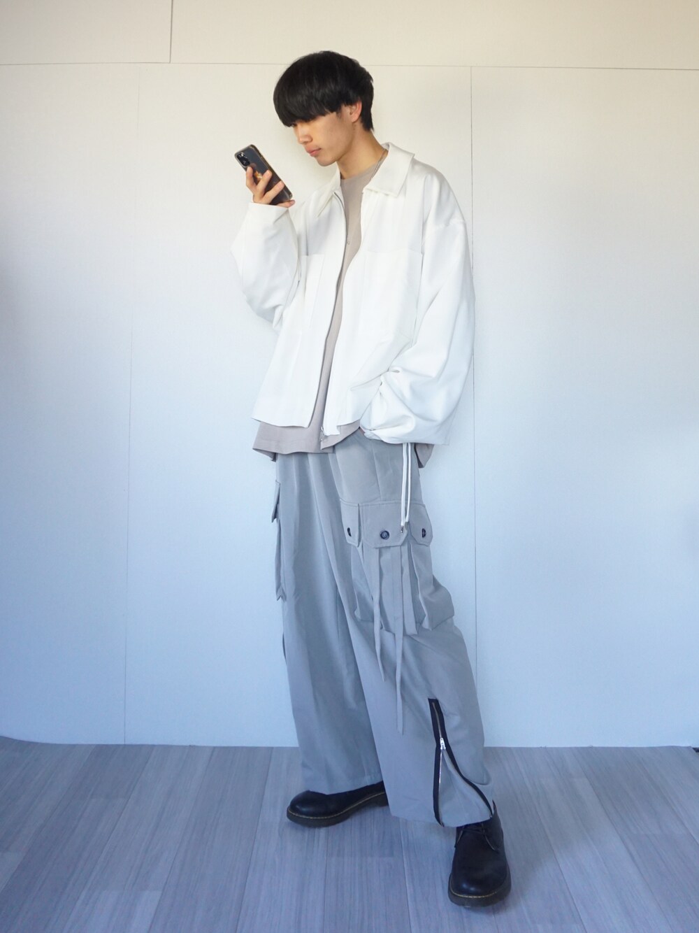 ベージュ系のTシャツ/カットソー、ホワイト系のブルゾン、グレー系のカーゴパンツを着用したメンズの秋コーディネートの1枚目の写真